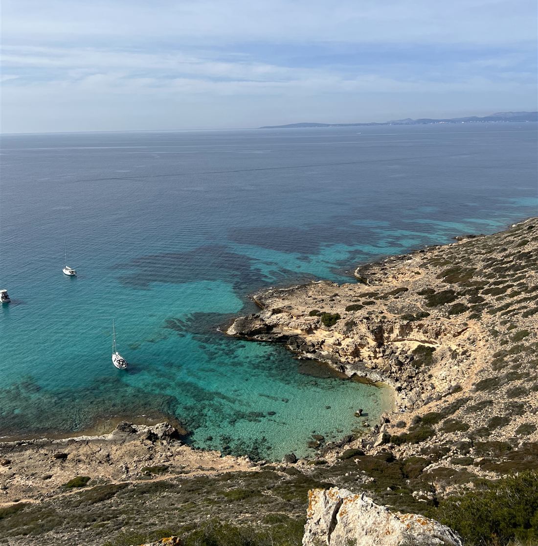 A turquoise cove on the Mallorcan coast with small boats at anchor