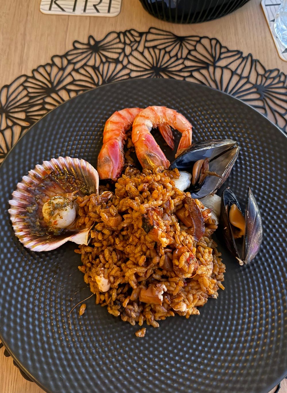A seafood and rice dish served on a dark plate at a Mallorcan restaurant