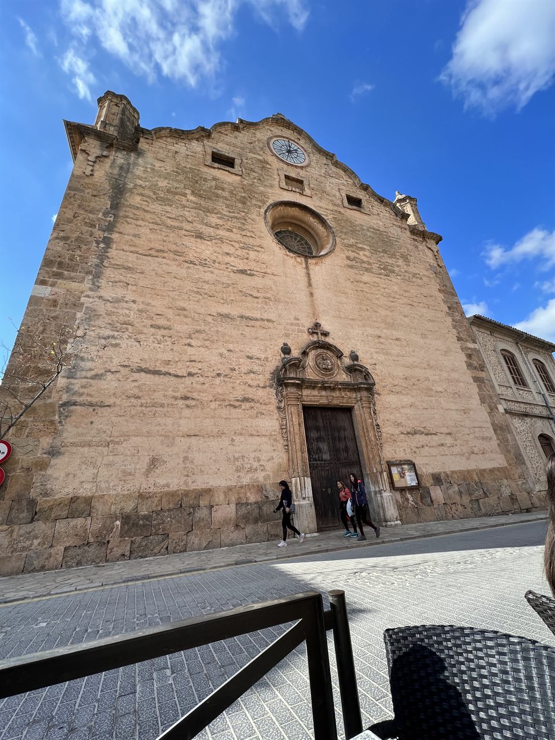 The stone facade of a parish church on a Mallorcan town square