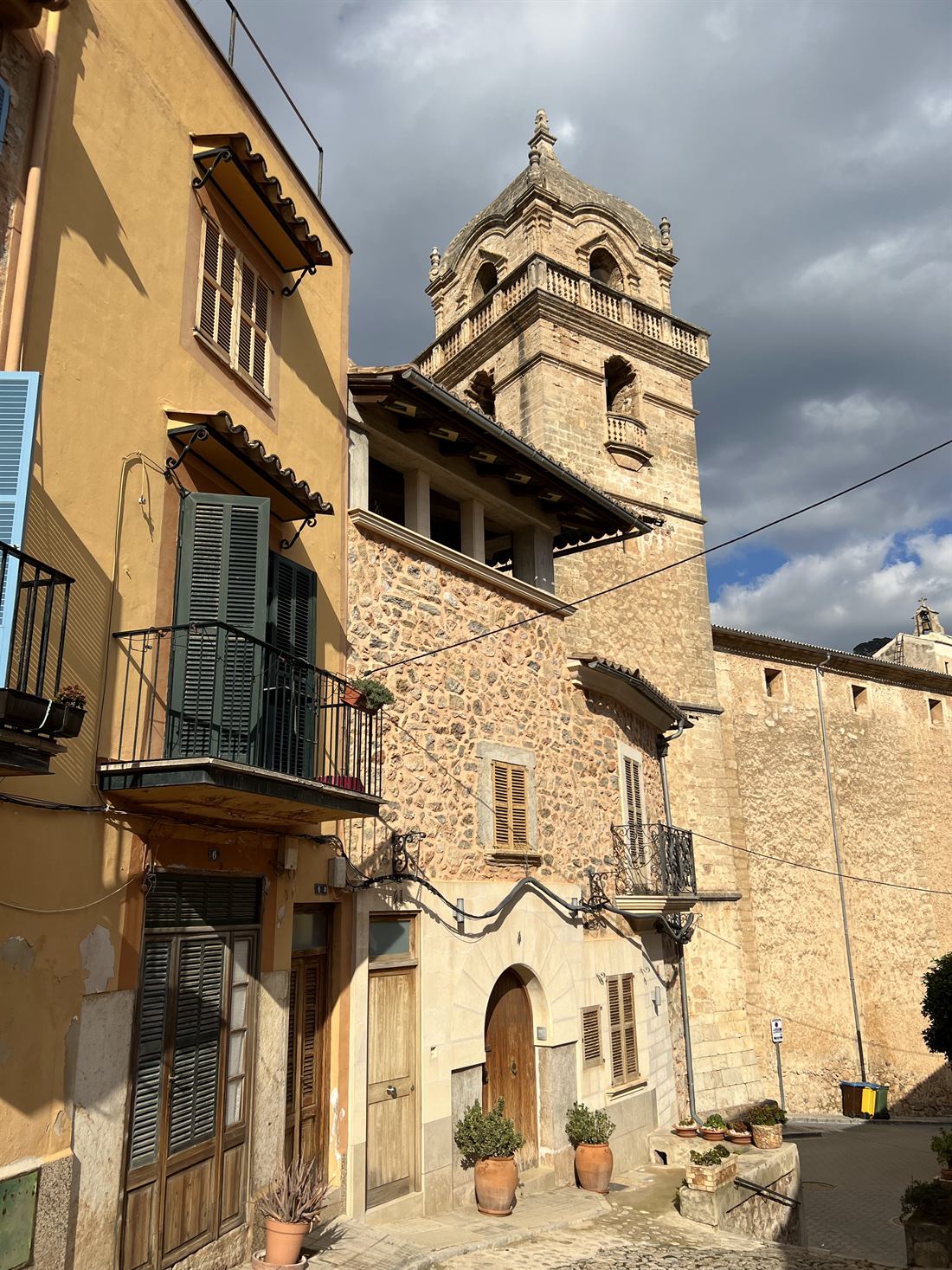 A narrow village street in Mallorca with stone houses and a church bell tower